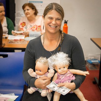 Woman smiling, holding two dolls