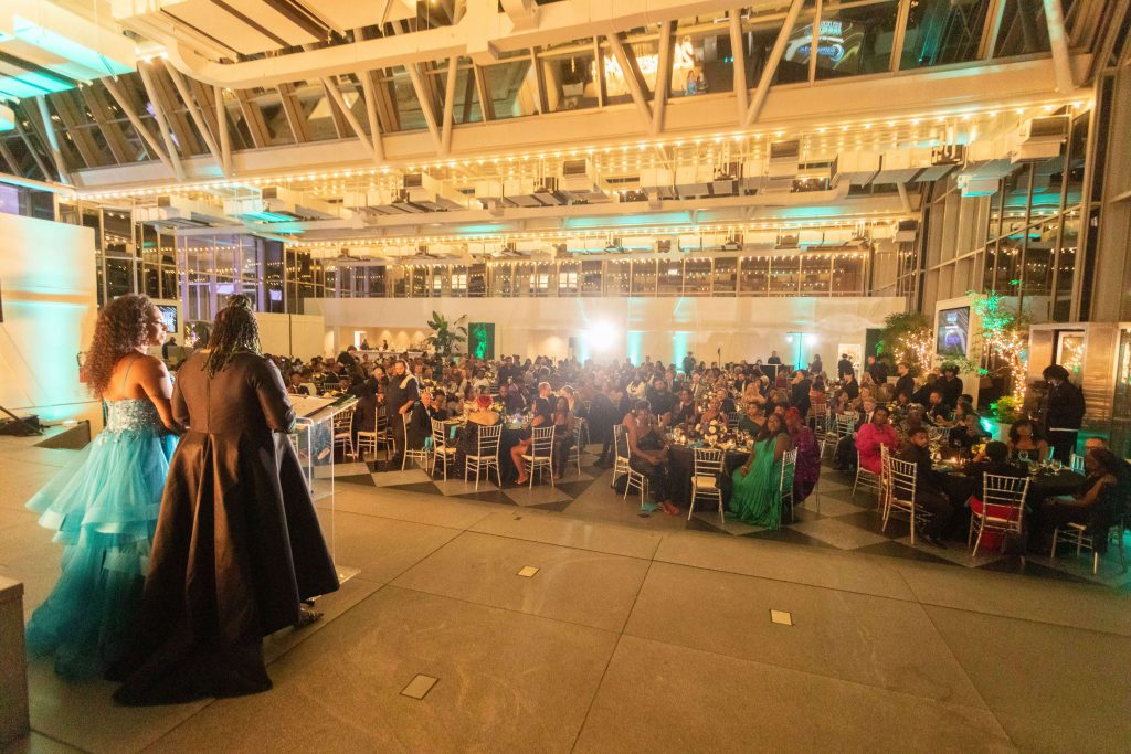 BERE Gala attendees sitting at their tables while Tammy and Mary give a speech on stage