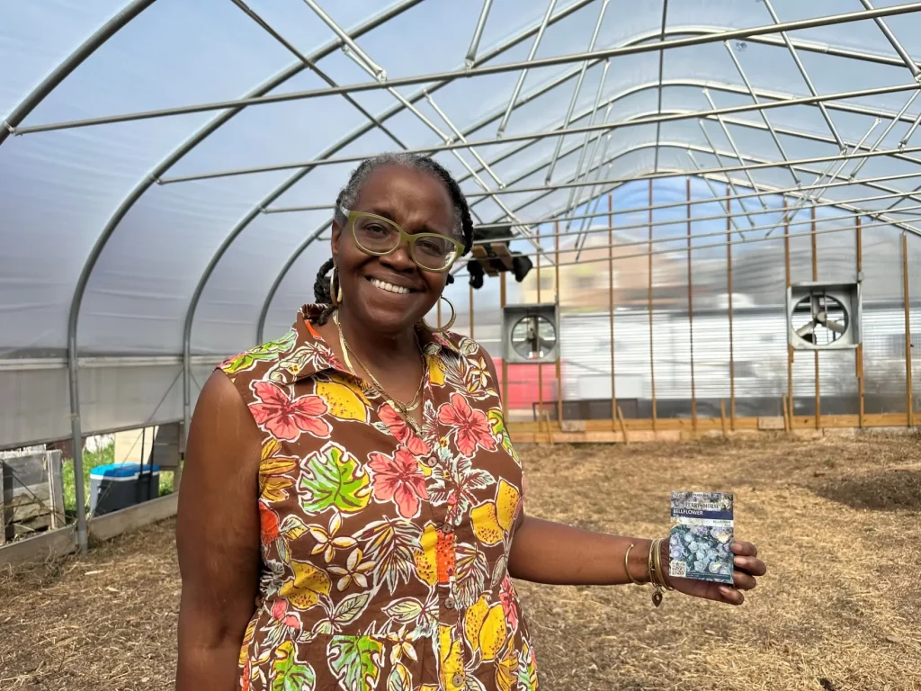 Lisa Freeman holding up seeds in a greenhouse