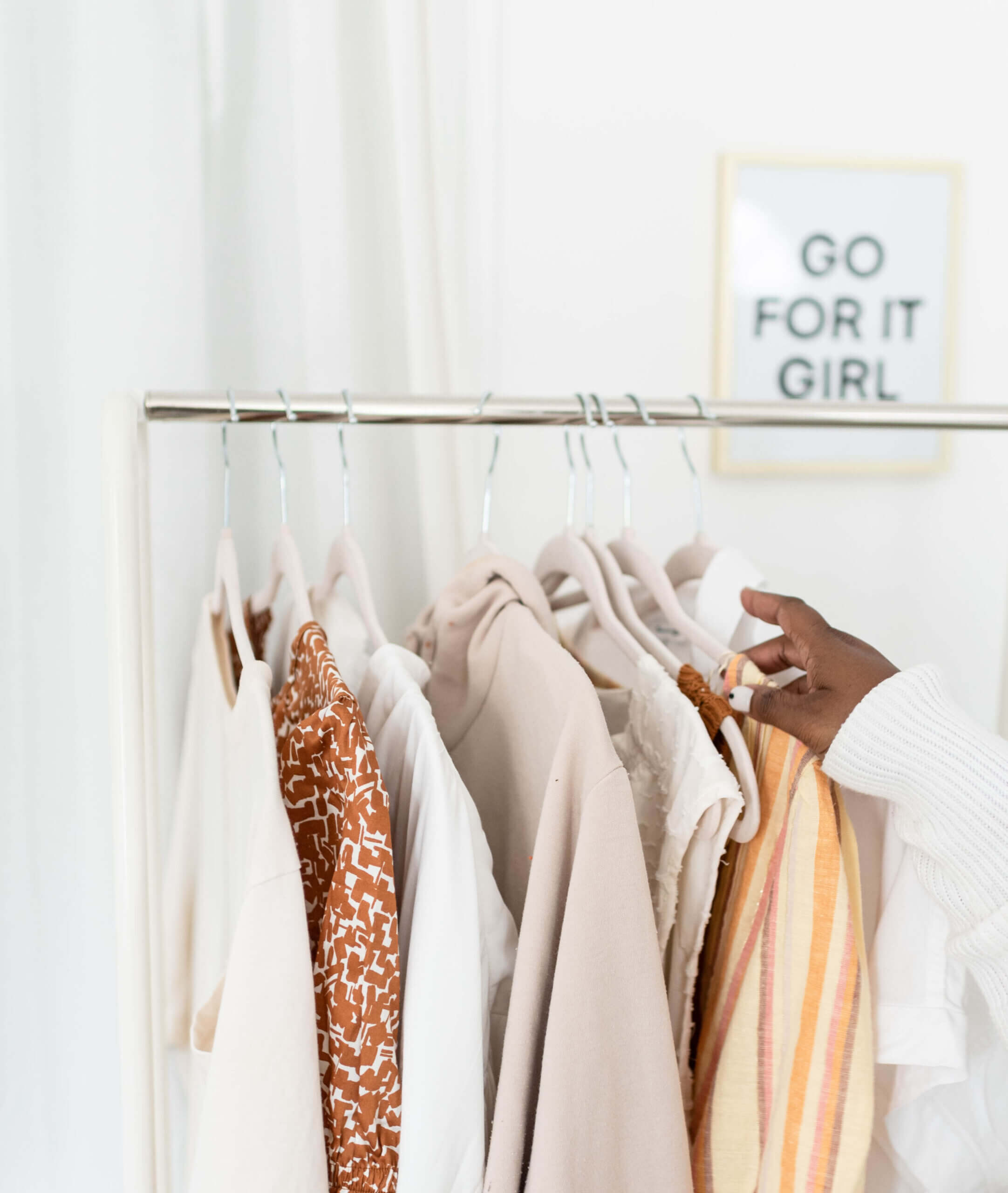 Hand reaching out to touch garments hung on a rack