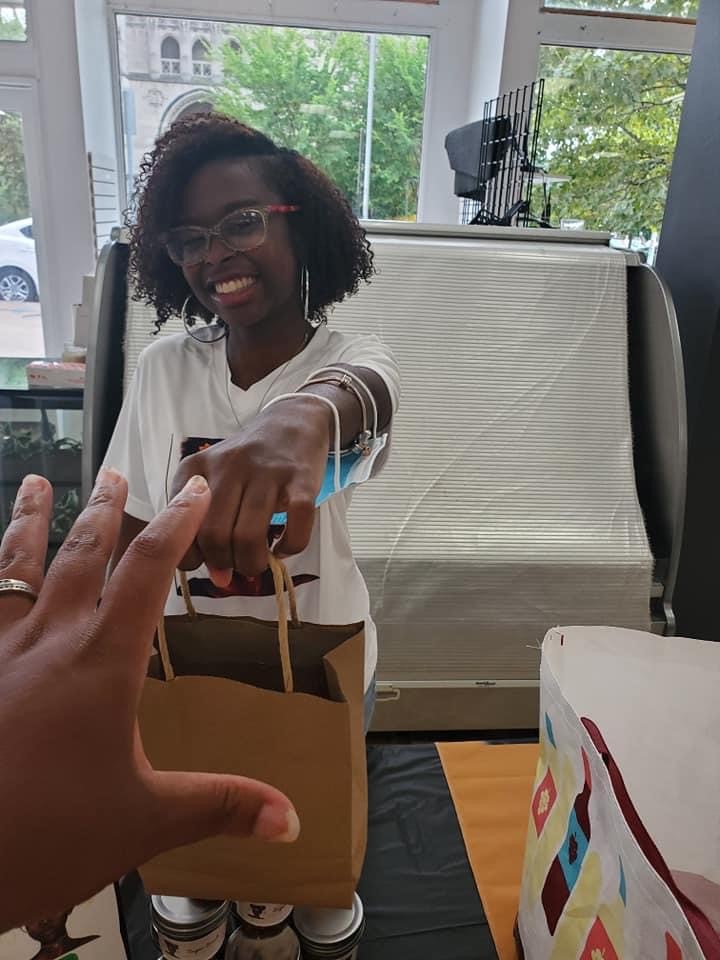 Catapult Kids graduate Jillian Lavender-Kalon Beauty hands a shopping bag to a customer while smiling