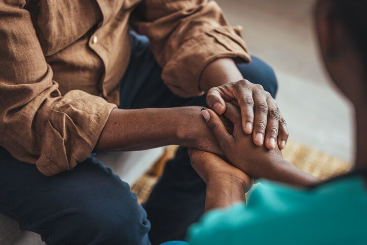 Two people holding each other's hands in a comforting manner